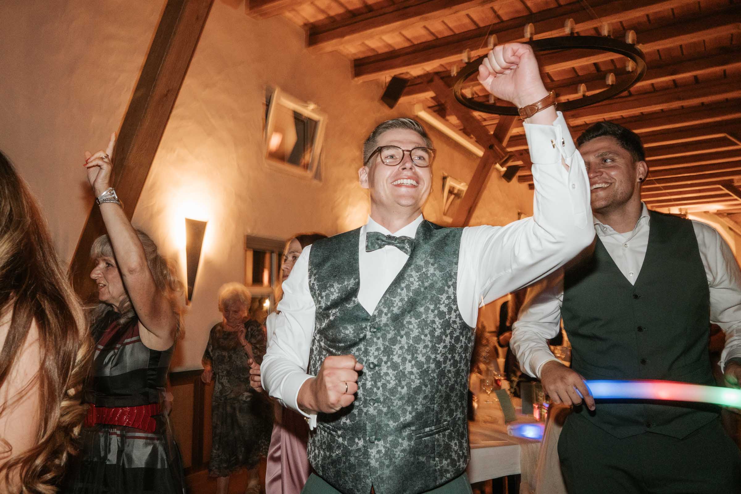 Bräutigam jubelt tanzend, Freunde feiern mit.