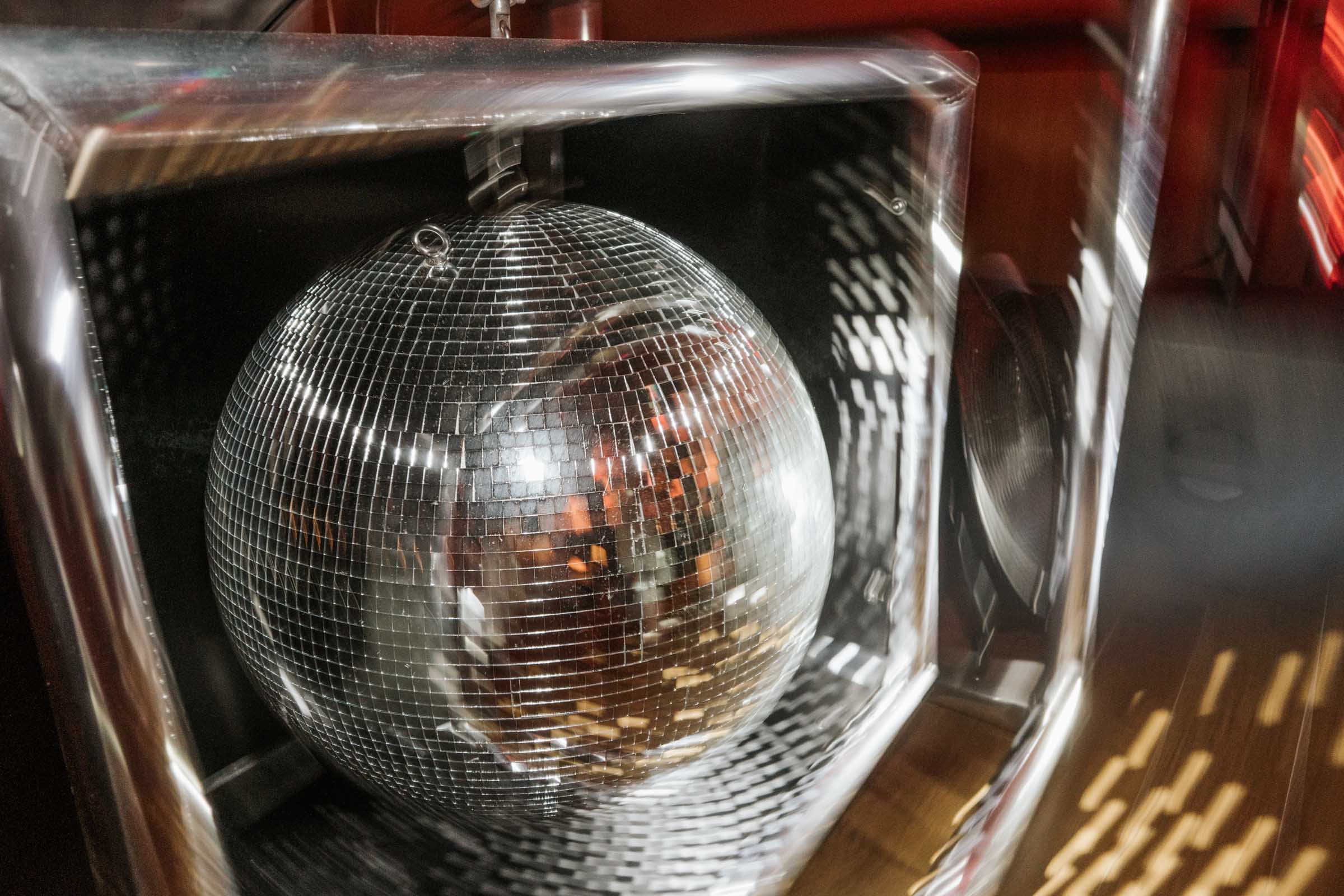 Nahaufnahme einer beleuchteten Discokugel am DJ-Pult.