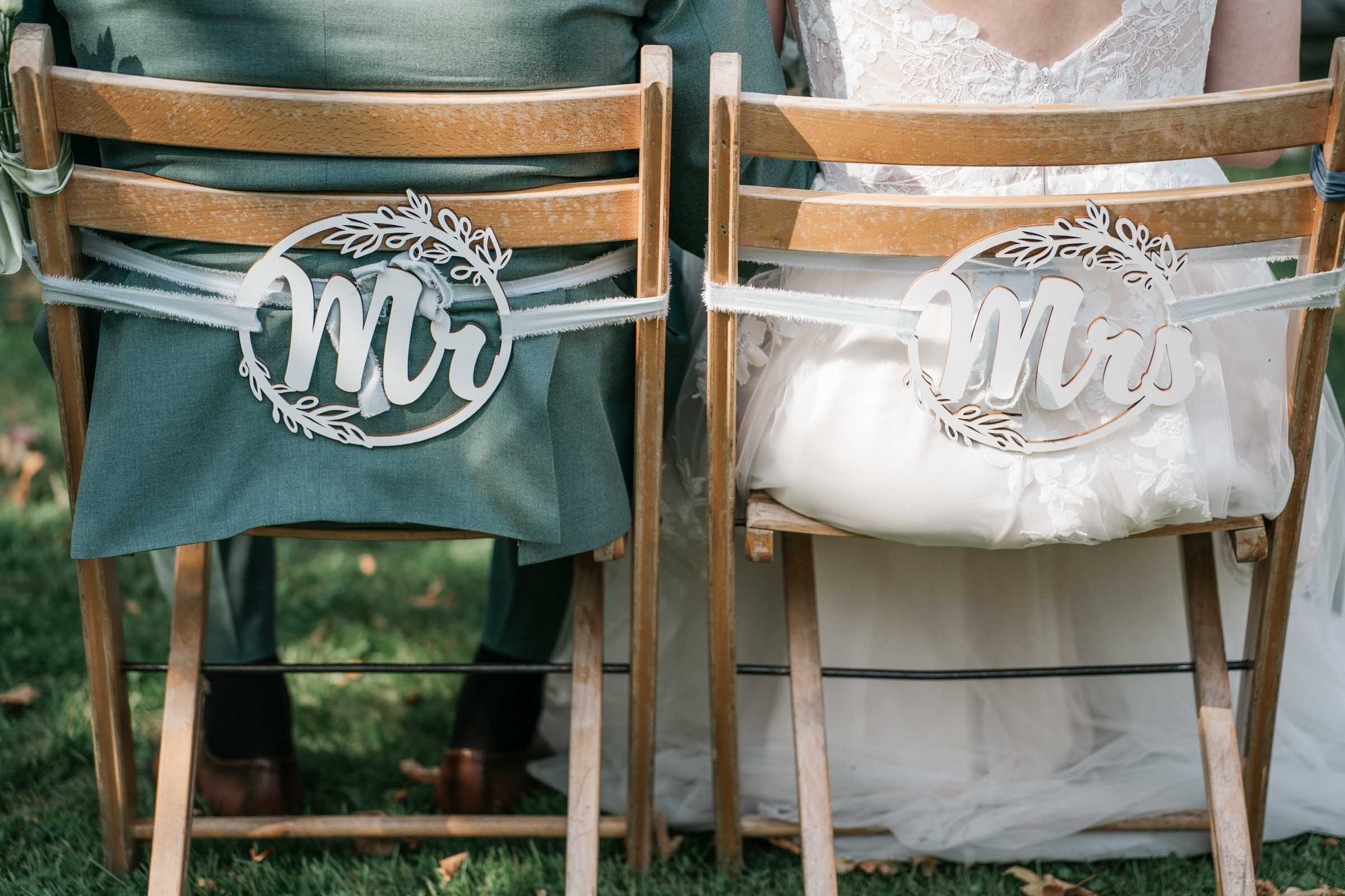 Nahaufnahme der dekorierten Stühle des Brautpaares mit „Mr/Mrs“.