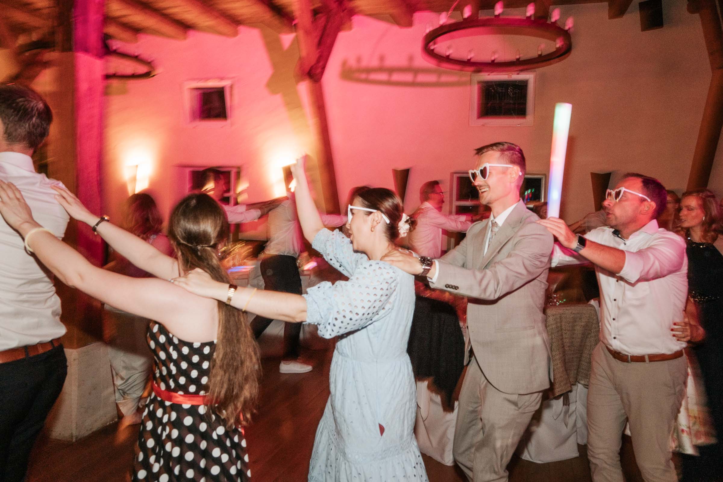 Gäste bilden eine Polonaise mit Herzbrillen und LED-Sticks.