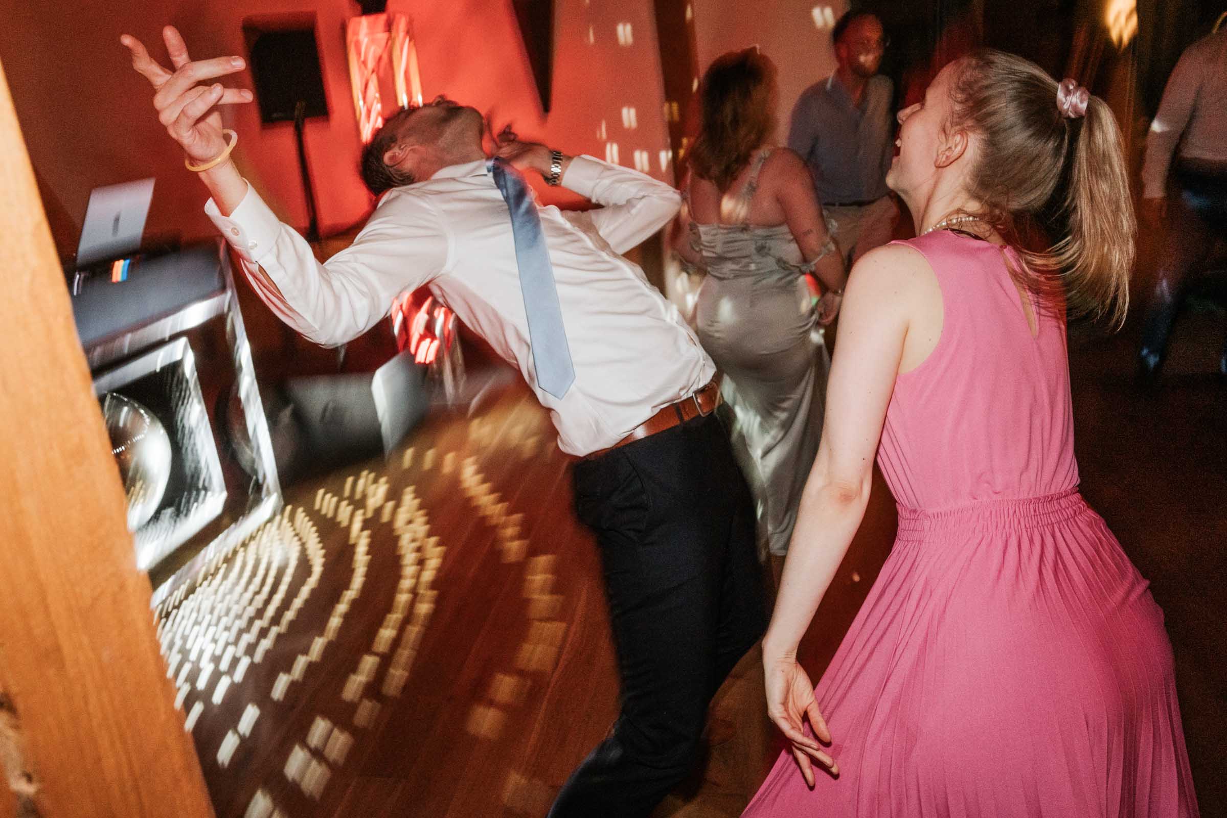 Gäste tanzen ausgelassen; Lichtmuster der Discokugel auf dem Boden.