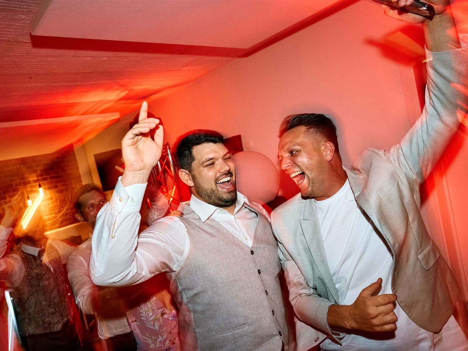 DJ Timm lächelt im Partylicht bei einer Hochzeit.