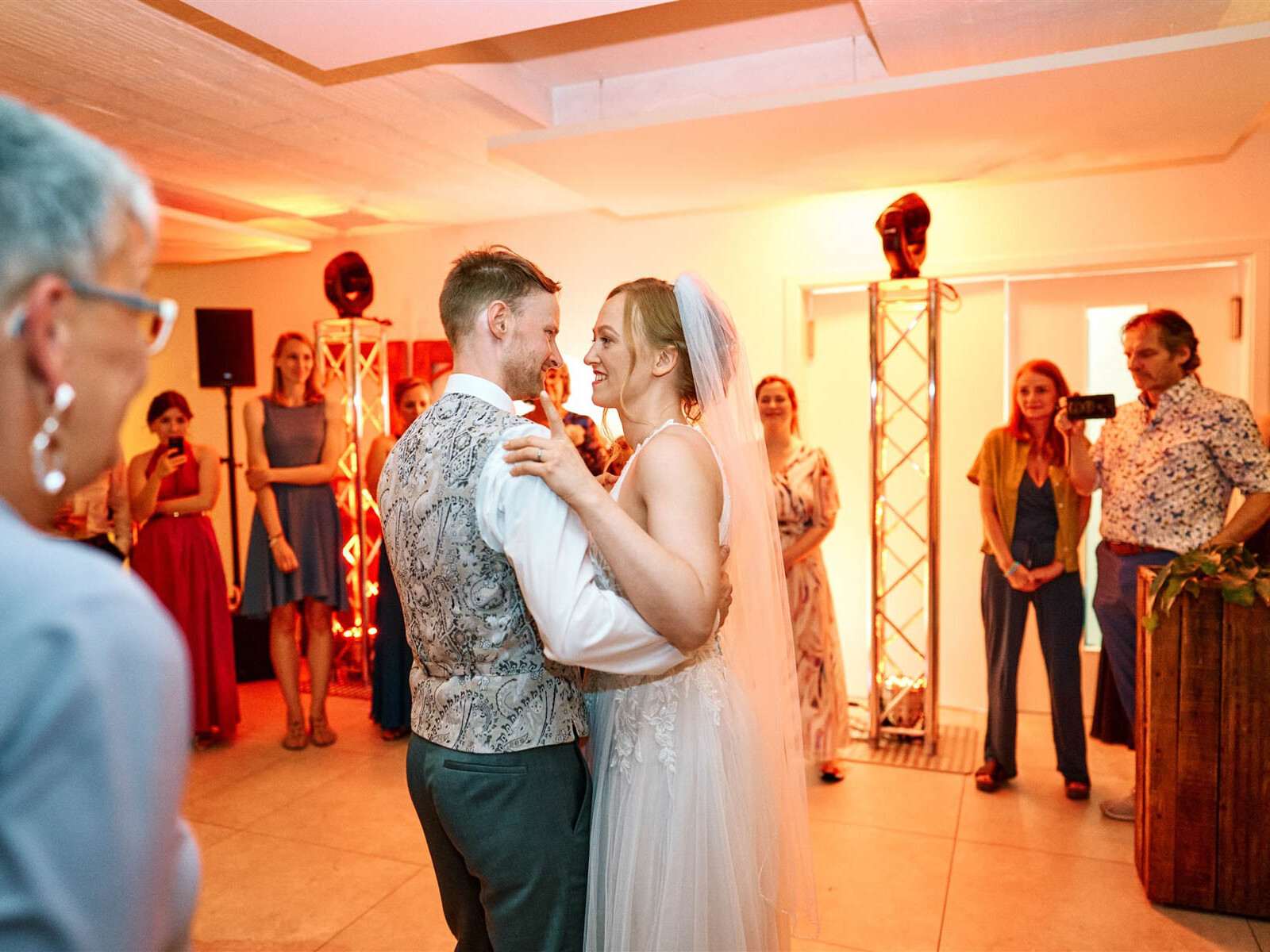 Braut und Bräutigam tanzen vor Lichtanlage.