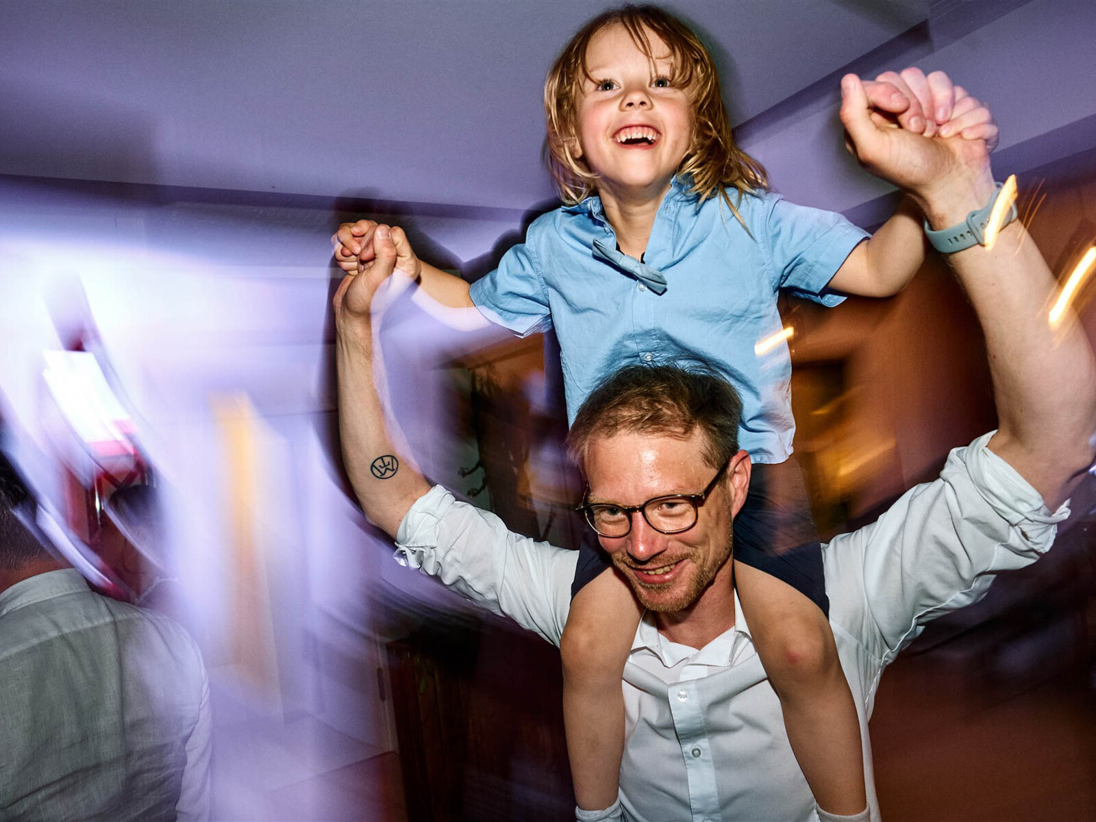 Kind sitzt auf Schultern und feiert bei der Hochzeit.