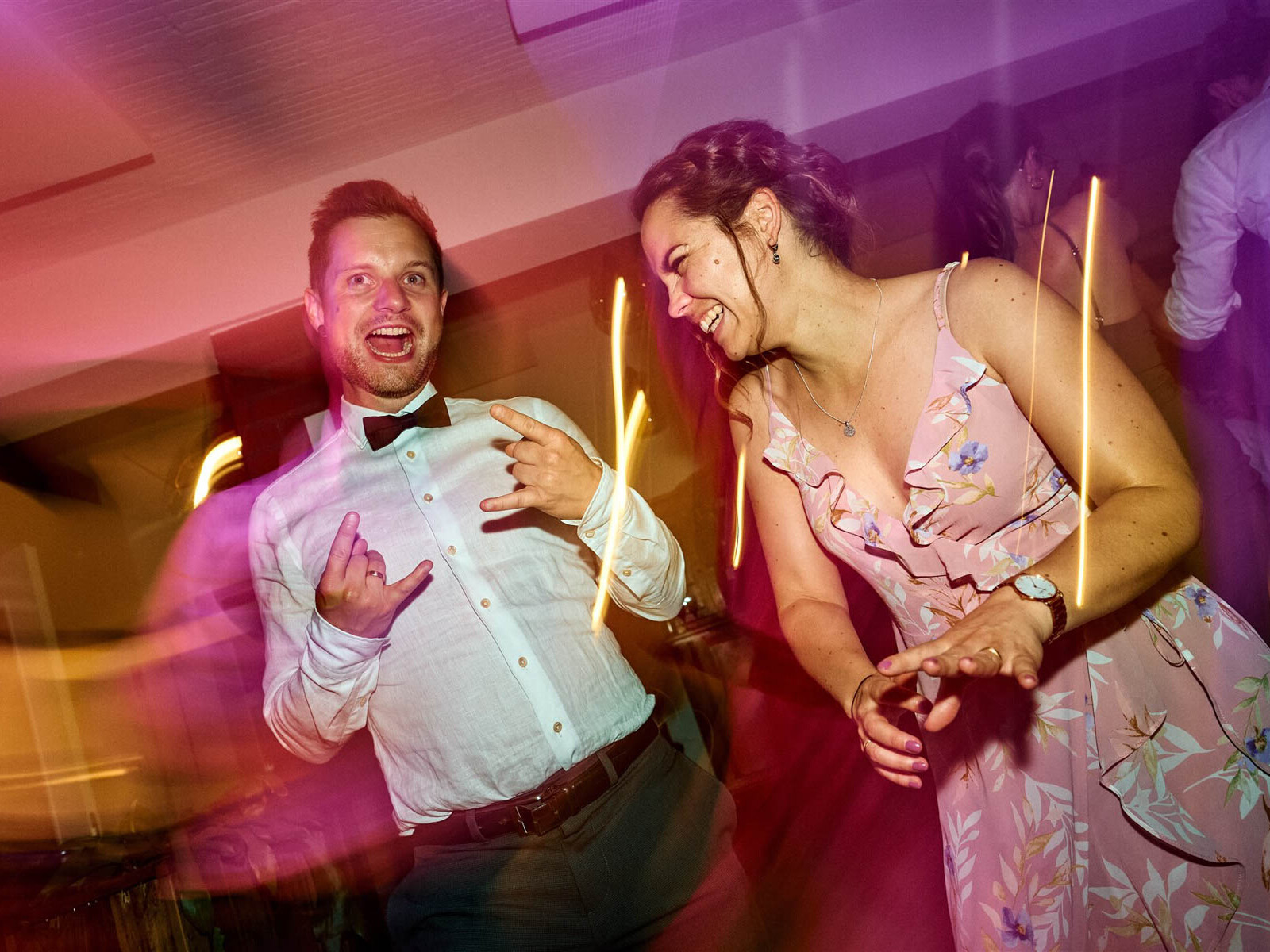 Zwei Gäste tanzen im bunten Licht.
